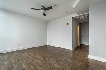 A room with a ceiling fan and wooden flooring.
